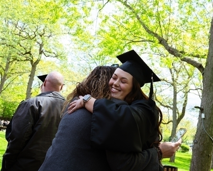 Grads in regalia hugging outdoors