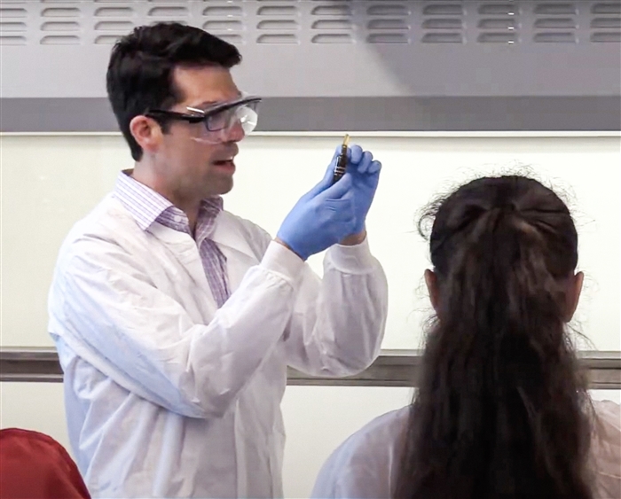 Professor in lab coat conducting in class experiment