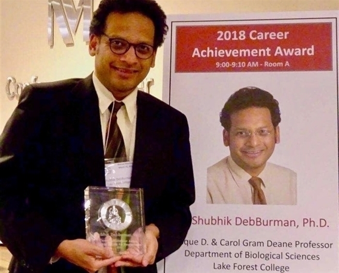 Professor holding his career achievement award trophy